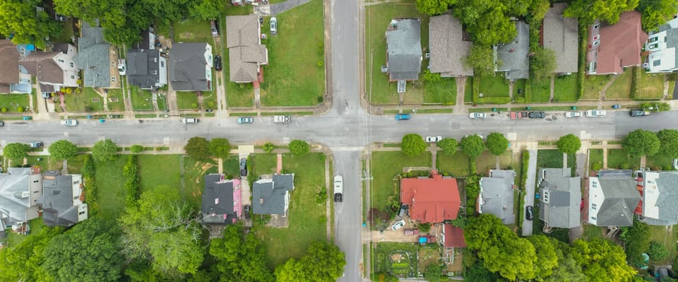 An overhead view of a residential intersection with houses, yards, and trees
