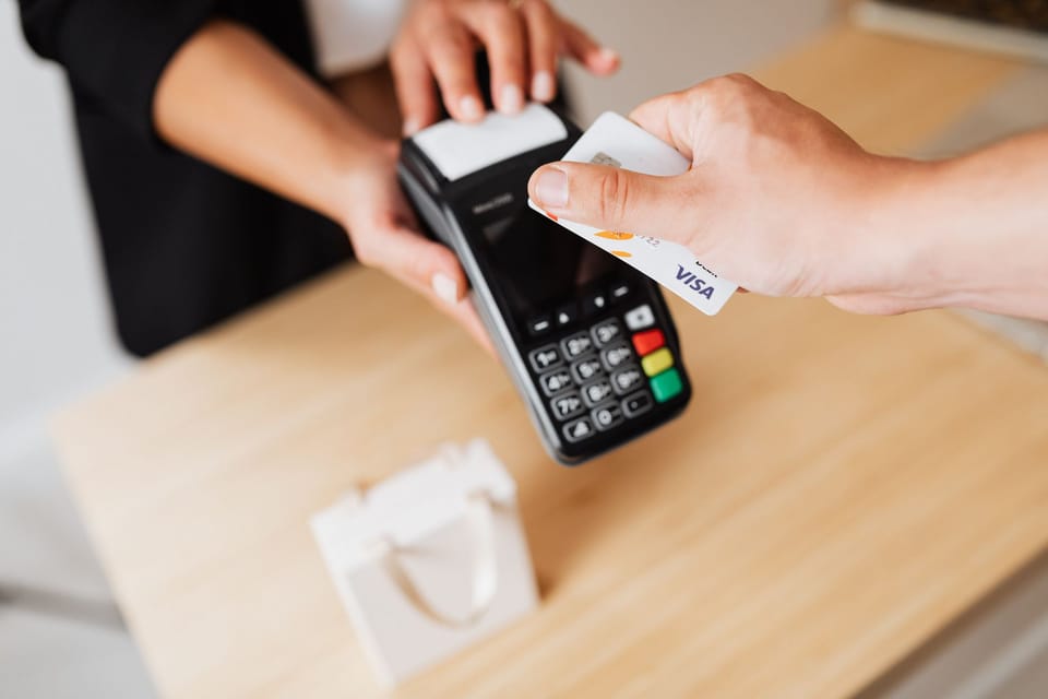 A hand holding a bank card to a card reader across a counter